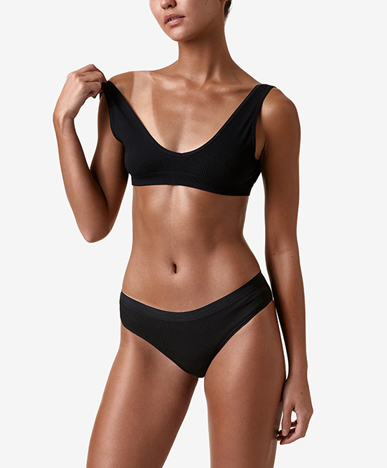 Model wearing a black bikini with a dark Bondi Sands spray tan