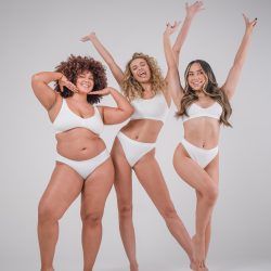 Group of three women in white bikinis tanned with Sienna X