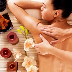 Woman experiencing a relaxing body massage surrounded by flowers and candles