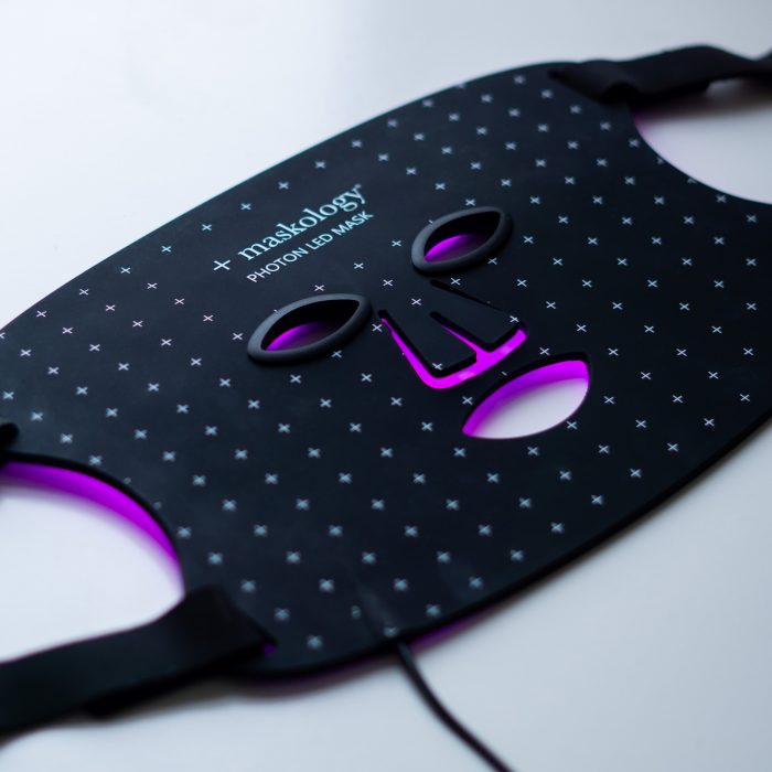 Flatlay image of the +maskology LED light mask on purple LED light therapy settings
