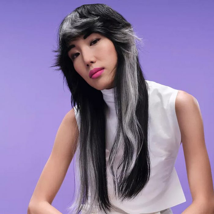 Wella monochromatic colour blocking model with long black and silver two tone hair on a purple background