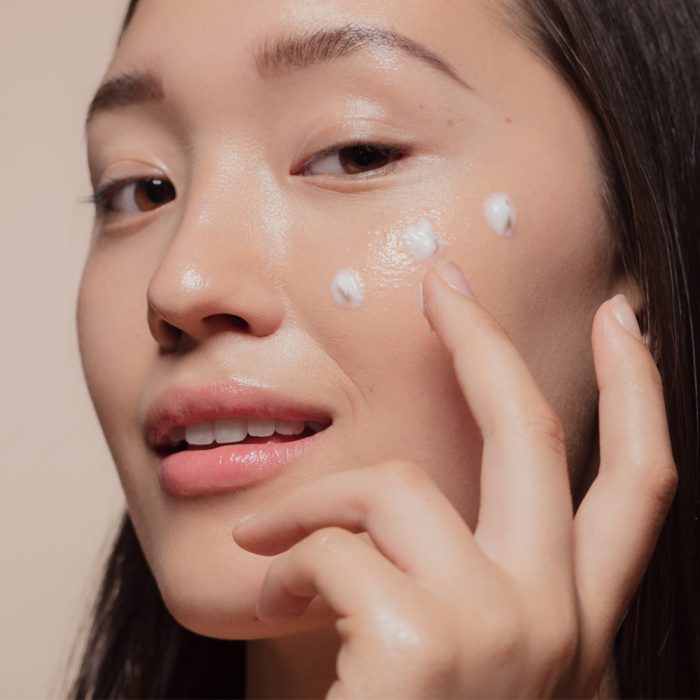 The best winter skincare tips blog. Woman applying moisturiser to cheek.