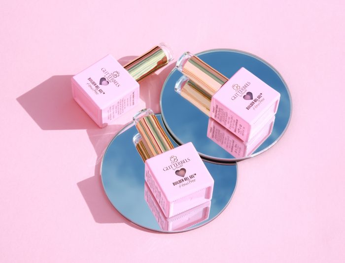 Three bottles of Glitterbels hema-free gel polish on circular mirrors against a pink background