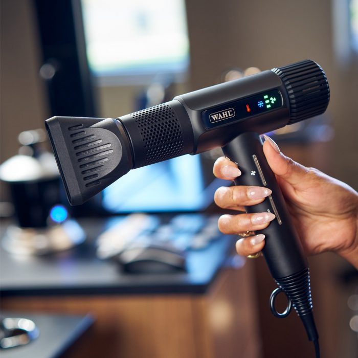 Wahl Vanquish hair dryer in hand in front of a professional barbering work station