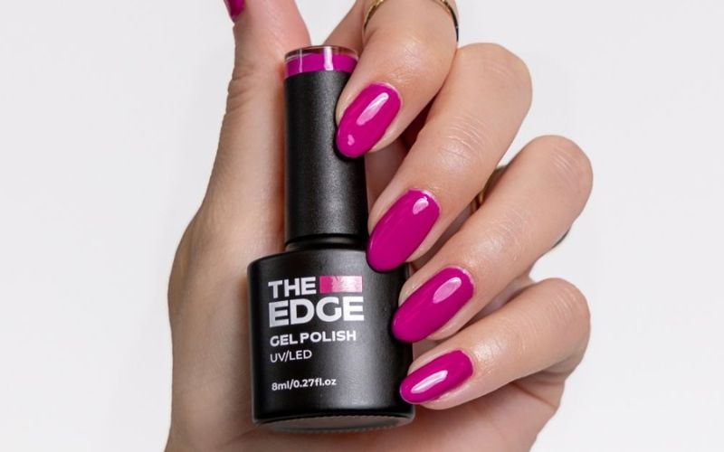 picture showing woman's hand with bright pink nails holding the edge nail polish bottle