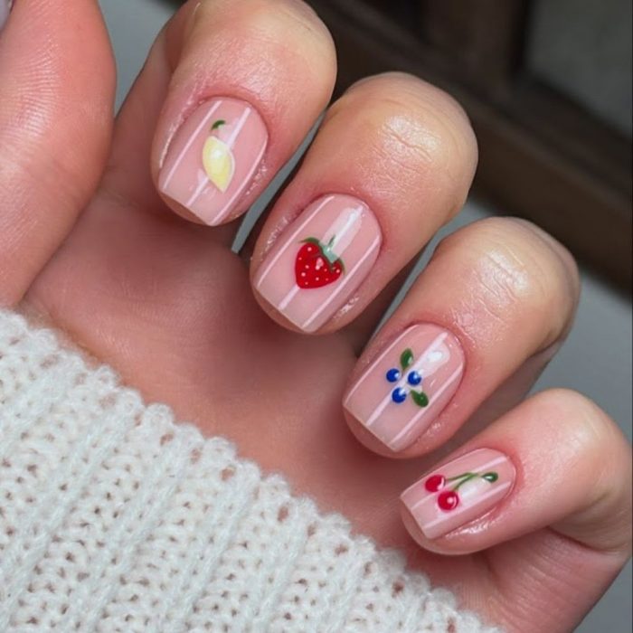 nude nails with white stripe and a different fruit on each nail
